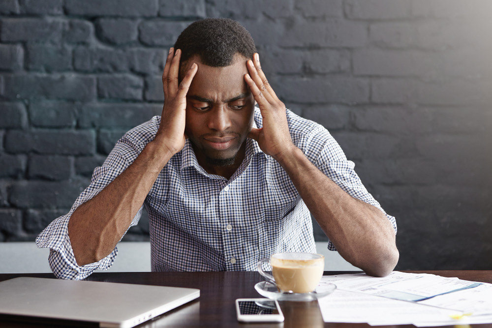 An exhausted office worker with a hand to his forehead